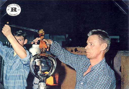 Karl Gustav Svensson (höger) klipper av ett ämne som ska bli en fot på en punschbål. Ämnet hålls fram av Håkan Ohlsson.